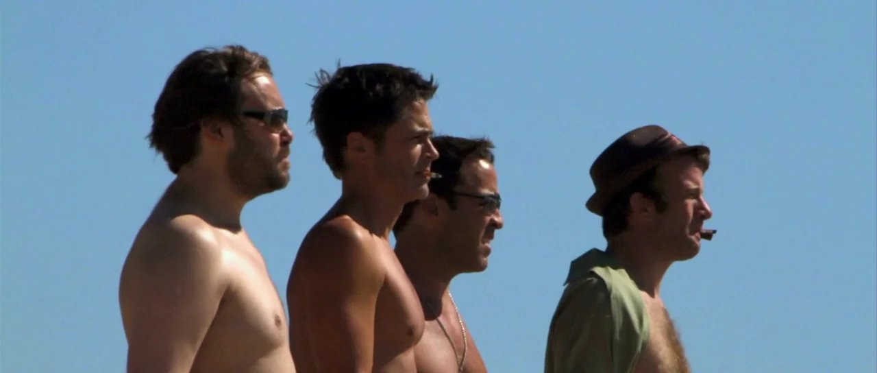 I Melt With You (2011) movie still: medium — Four men stand shoulder to shoulder against a clear blue sky. The men look toward the right while…
