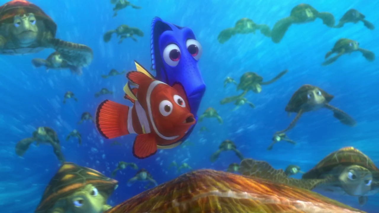 Finding Nemo (2003) movie still: medium — A group of sea turtles swims through deep blue water during the day. A small clownfish and a blue tang…