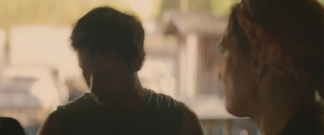 Holiday Harmony (2022) movie still: medium — An outdoor area with bright backlit elements blurring the background behind two people. A man and woman…