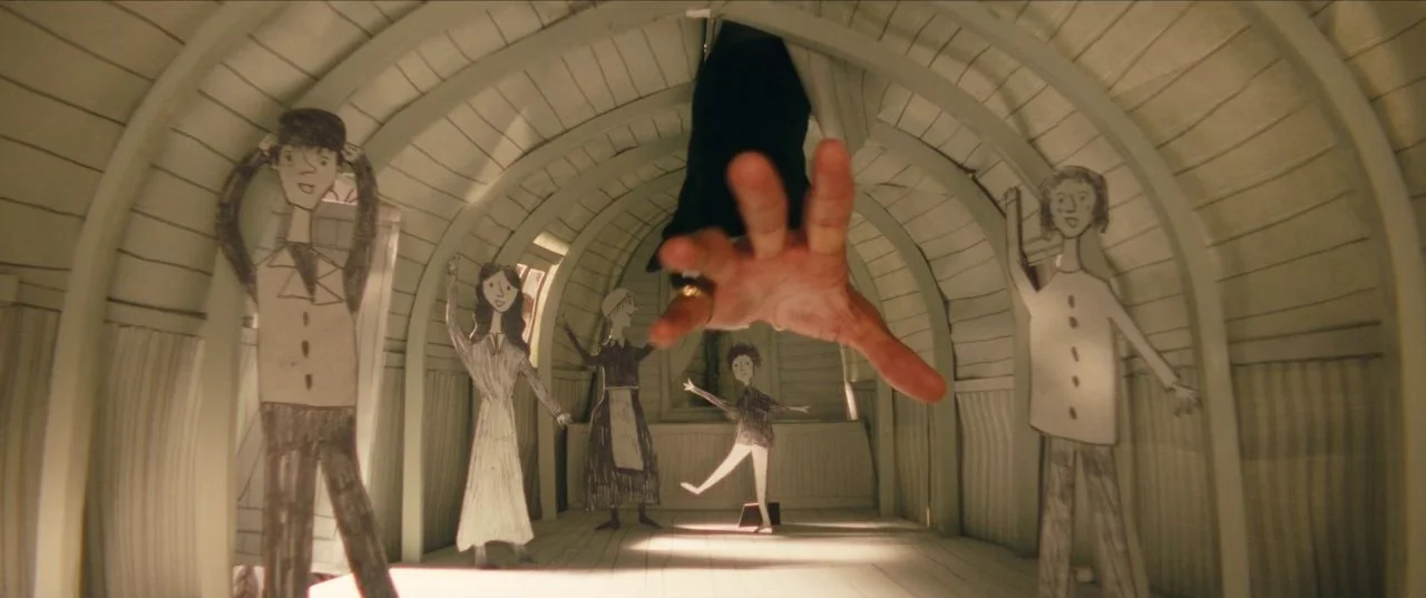 The Personal History of David Copperfield (2019) movie still: medium — A miniature wooden room contains several hand-drawn paper cutouts of people…