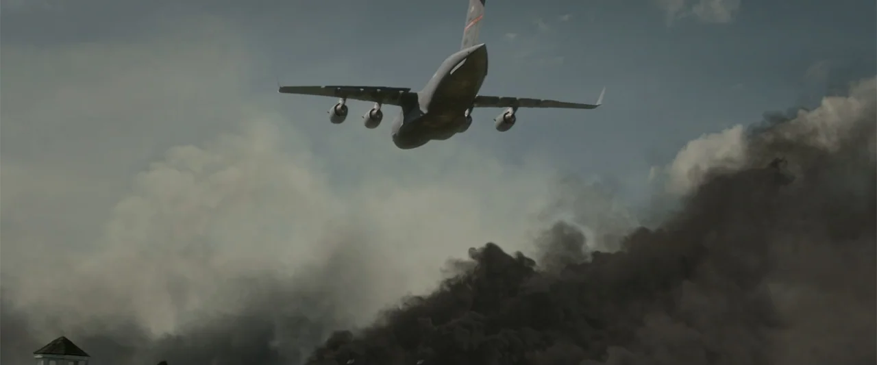 Godzilla (2014) movie still: wide — A military transport aircraft flies against a backdrop of thick dark clouds and smoke. Dense black smoke billows…