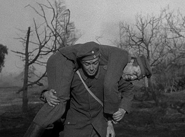 All Quiet on the Western Front (1930) movie still: fullbody — A desolate, barren landscape with skeletal trees under an overcast sky. A soldier…