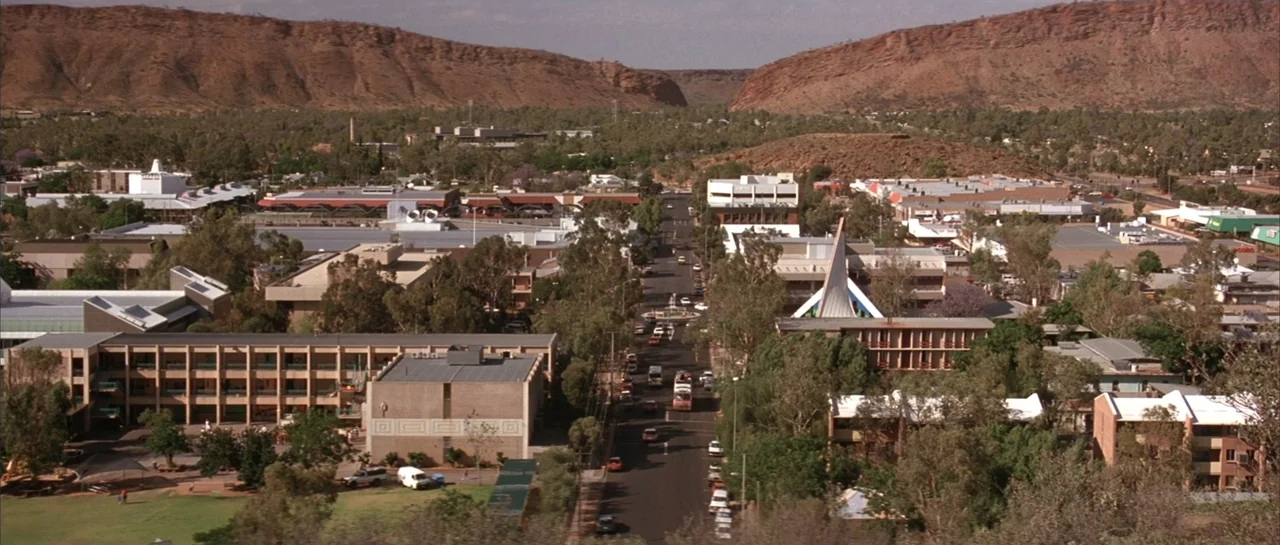 The Adventures of Priscilla, Queen of the Desert (1994) movie still: establishing — A wide aerial view of a town in an arid region with rugged red…