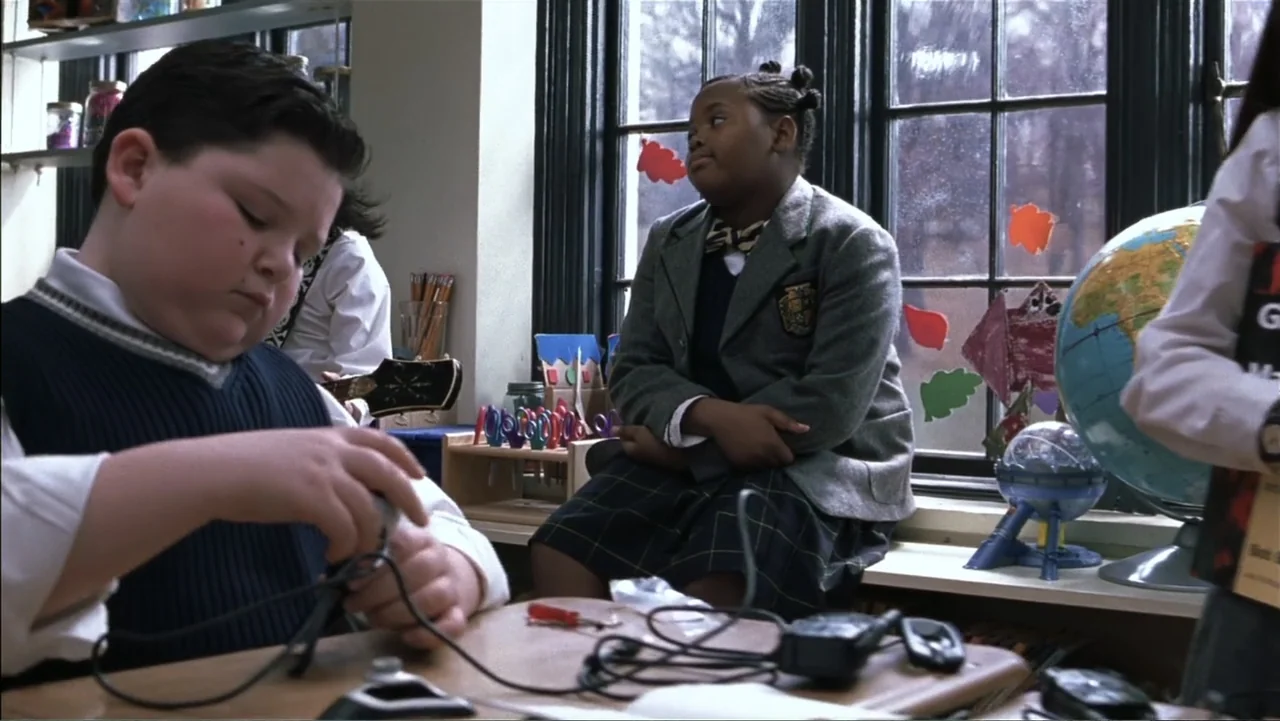 School of Rock (2003) movie still: medium — A school classroom features a large window with colorful cutout decorations on the glass. Two children…