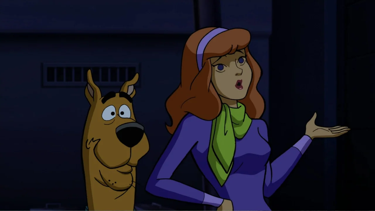 Scooby-Doo! Return to Zombie Island (2019) movie still: medium — An interior corridor with dark walls and a recessed ventilation grate. A woman and…
