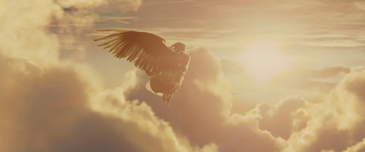 Maleficent (2014) movie still: wide — A figure with large bird-like wings flies through a dense layer of golden clouds. The sun glows intensely…