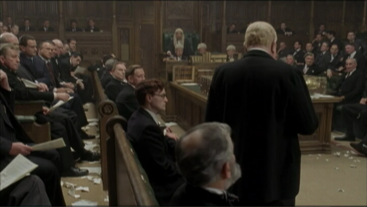 The Gathering Storm (2002) movie still: medium — A historic legislative chamber features dark wood paneling and rows of tiered benches. An elderly…