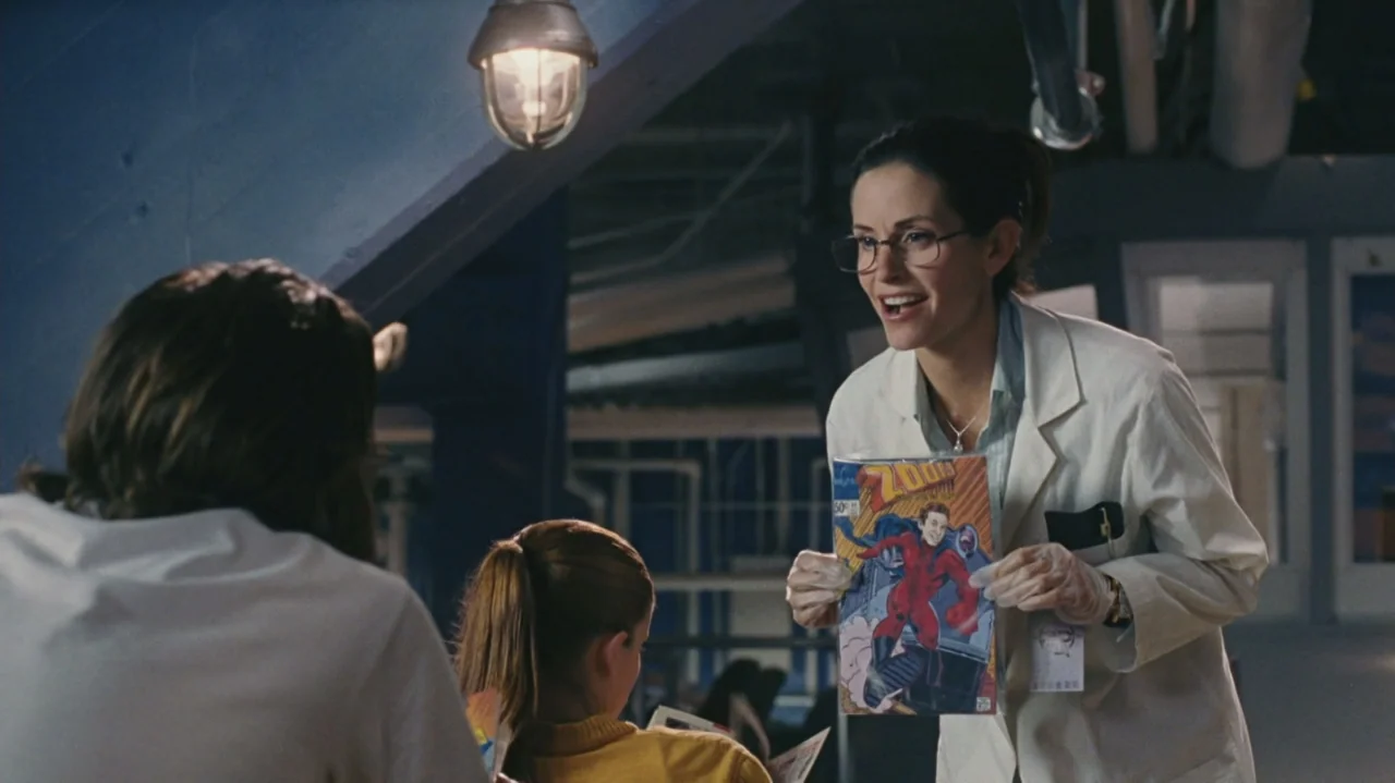 Zoom (2006) movie still: medium — A modern laboratory features white surfaces and cool blue shadows in the background. A woman wearing a lab coat…