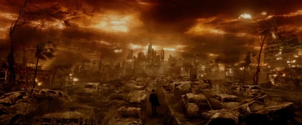Constantine (2005) movie still: wide — A desolate urban landscape is choked with charred debris and rows of rusted vehicles. A solitary man in a…