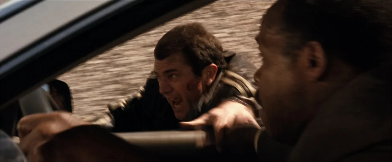 Lethal Weapon 4 (1998) movie still: medium — The interior of a moving car shows two men in mid-motion. One man reaches for the steering wheel while…