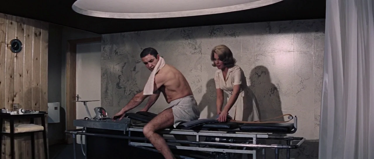 Thunderball (1965) movie still: medium — A modern health facility features light wood paneling, patterned wallpaper, and metallic exercise…