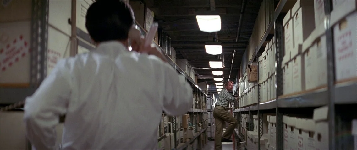 The Hunt for Red October (1990) movie still: medium — Rows of metal shelving stacked with white document boxes fill a narrow aisle. A man standing…