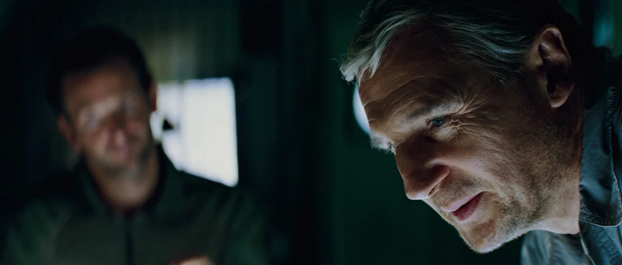 The A-Team (2010) movie still: medium — A dimly lit interior space with shadows obscuring most of the surrounding area. An older man in the…