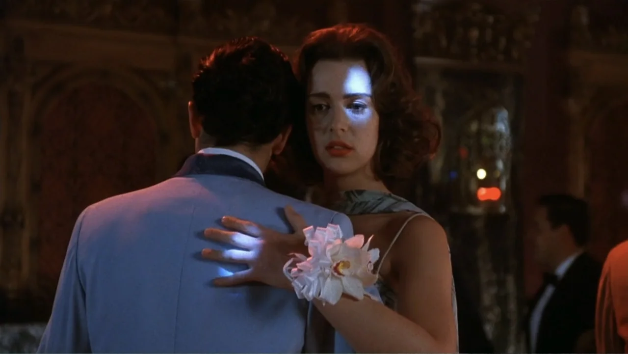 The Mambo Kings (1992) movie still: medium — A dimly lit ballroom with indistinct decorations and people in the background. A young couple dances…