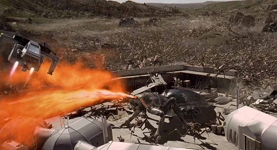 Starship Troopers (1997) movie still: wide — A desolate desert outpost is surrounded by a massive swarm of insectoid creatures. One large insect…