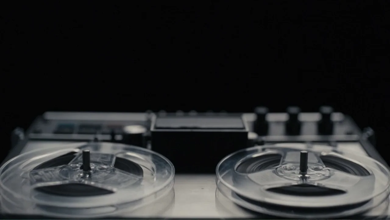 Elizabeth Taylor: The Lost Tapes (2024) movie still: closeup — A close-up view of a vintage reel-to-reel tape recorder sits on a flat surface. The…