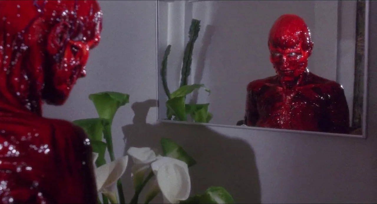 Hellbound: Hellraiser II (1988) movie still: medium — A stark white interior wall features a rectangular mirror and a potted plant. A skinless,…