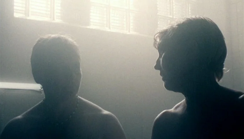 Maelström (2000) movie still: medium — A tiled room features a large window with horizontal blinds behind two people. Two men sit together in…