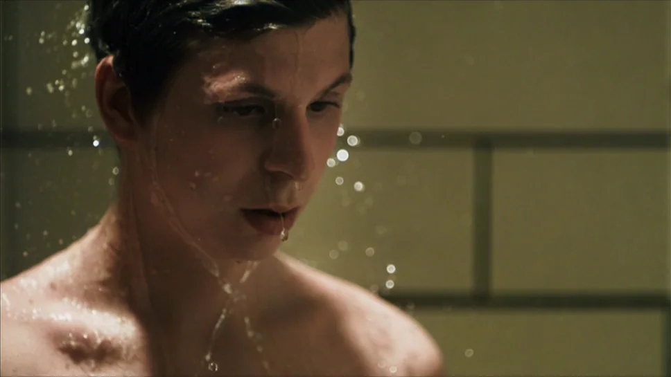 Youth In Revolt (2009) movie still: closeup — A tiled wall serves as the background in this close up view. A person stands with their face and hair…