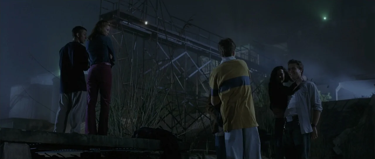 A Walk to Remember (2002) movie still: wide — An industrial water canal site features a metal gantry and tall reeds at night. A group of five young…