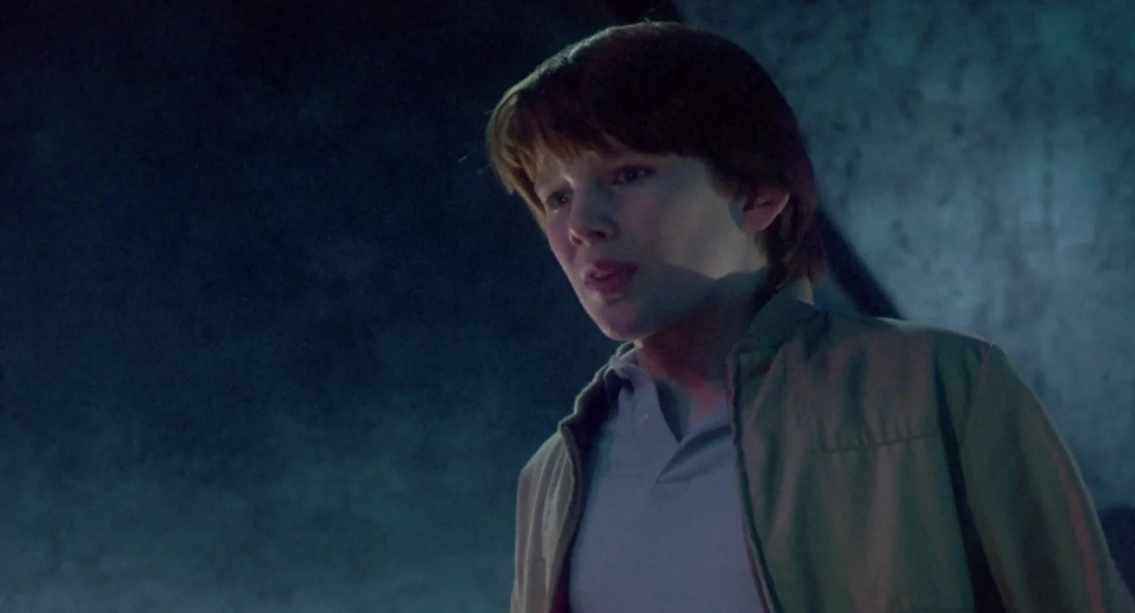 Explorers (1985) movie still: medium — A dark, dimly lit environment provides a stark contrast to the illuminated subject. A young boy looks…