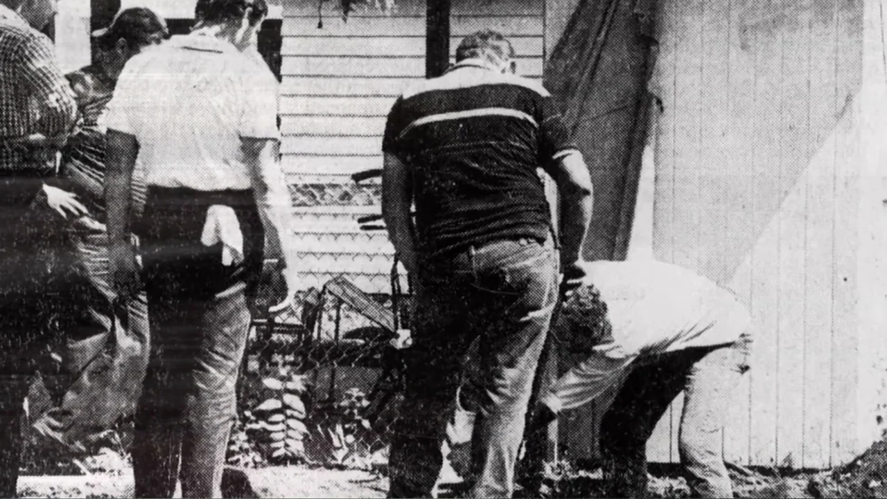 Murders at the Burger Joint (2022) movie still: medium — Four individuals gather against a wooden paneled wall in a residential backyard area. One…