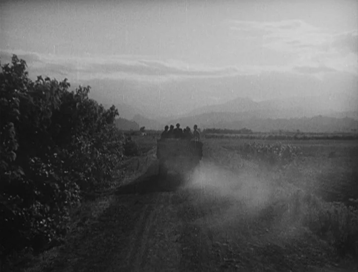 No Regrets for Our Youth (1946) movie still: wide — A rural dirt road stretches toward distant mountains under a cloudy sky. A cart carrying several…