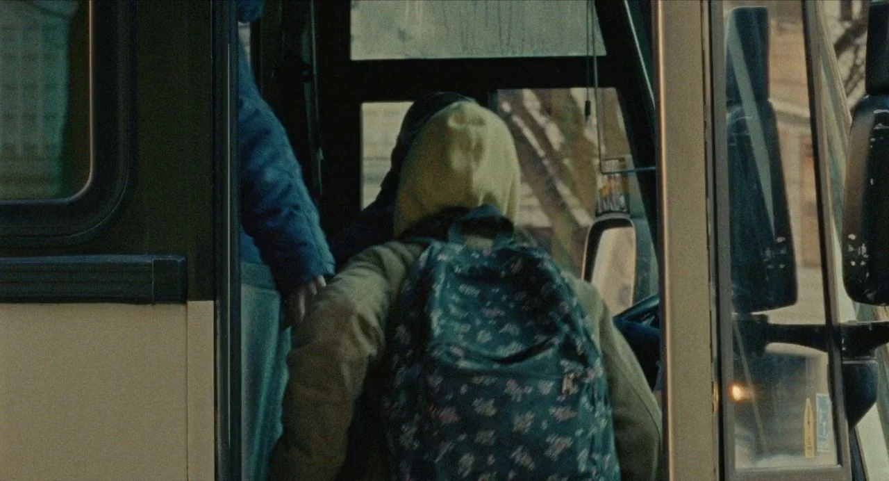 Never Rarely Sometimes Always (2020) movie still: medium — The front interior of a passenger bus with glass doors and metal handrails. A student…