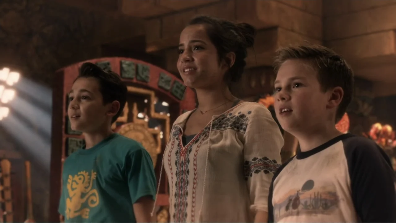 Legends of the Hidden Temple (2016) movie still: medium — A stone chamber features carved walls and an ornate, reddish-brown circular gateway in…