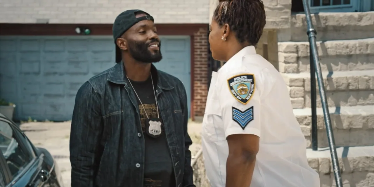 Equal Standard (2021) movie still: medium — A residential driveway with a grey garage door and stone steps in the background. A male officer in…