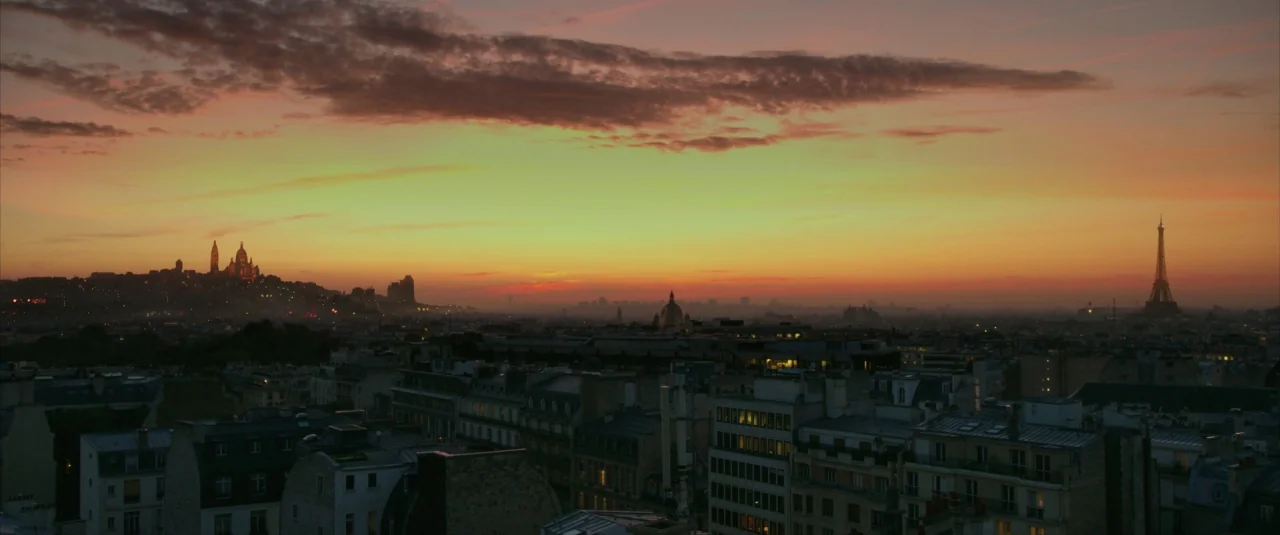 Lucy (2014) movie still: establishing — A sweeping aerial view of the Paris skyline at sunset featuring classic Haussmannian architecture. The…