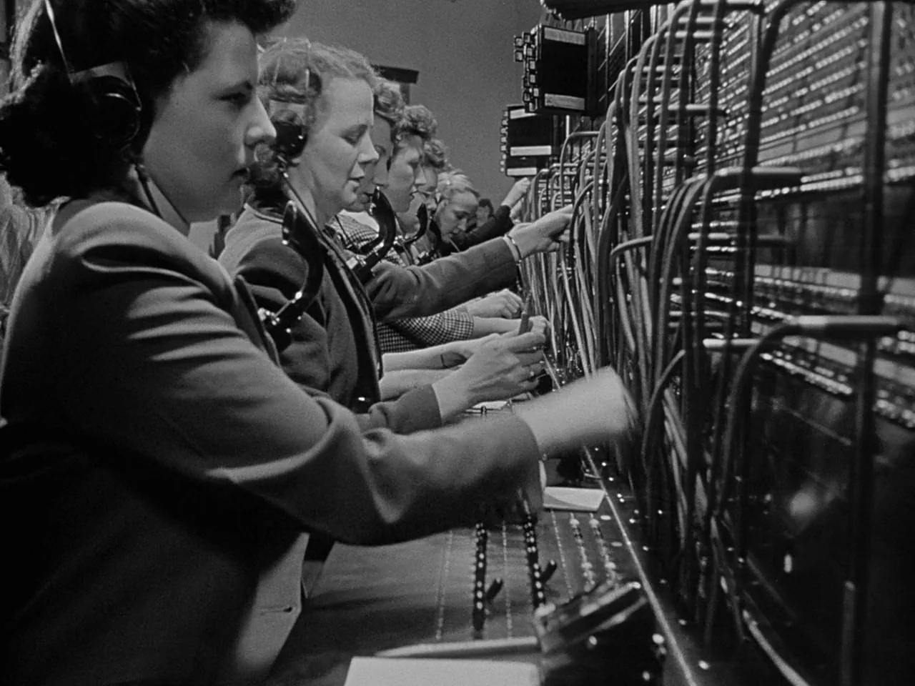 The Day the Earth Stood Still (1951) movie still: medium — A line of women sits at a large, complex telephone switchboard console. The operators…