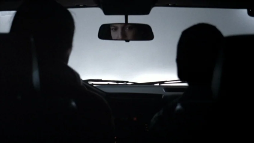 Benny’s Video (1992) movie still: medium — The interior of a car at night featuring two dark figures in silhouette. A face is visible in the…