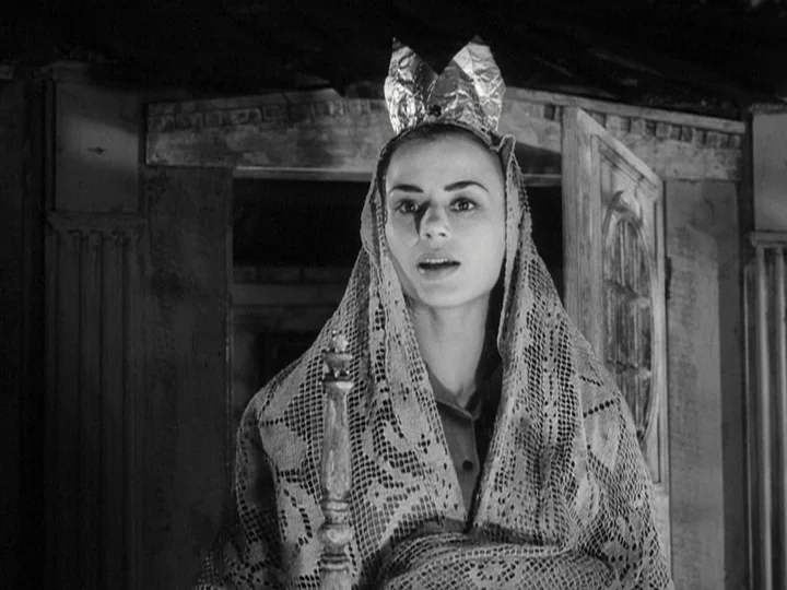 Through A Glass Darkly (1961) movie still: closeup — A dimly lit room features a woman wearing a makeshift crown and crochet shawl. She stares…