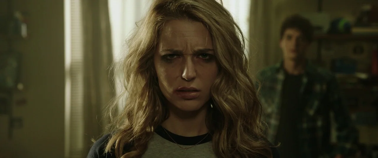 Happy Death Day (2017) movie still: closeup — A cluttered room interior with window blinds and soft light filtering from behind. A woman with…