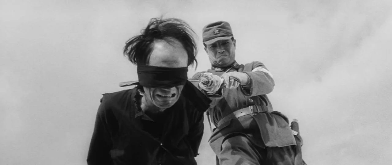 The Human Condition I: No Greater Love (1959) movie still: medium — A desolate outdoor environment with an overcast, bright sky background. A…