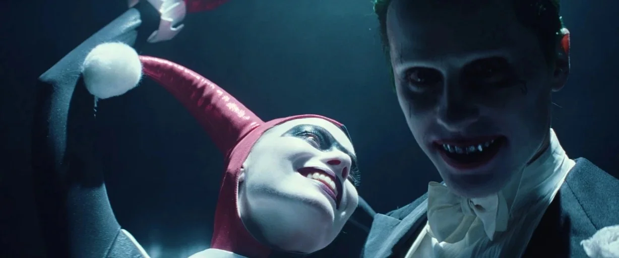 Suicide Squad (2016) movie still: medium — A dark environment with minimal visible architecture focuses on two figures in formal wear. The man and…