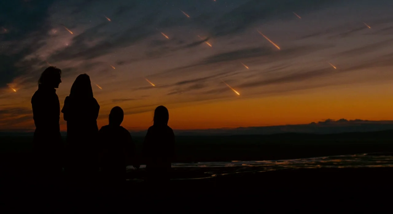 Noah (2014) movie still: wide — Four silhouettes stand on a dark field under a sky filled with falling meteors. The twilight horizon glows with…