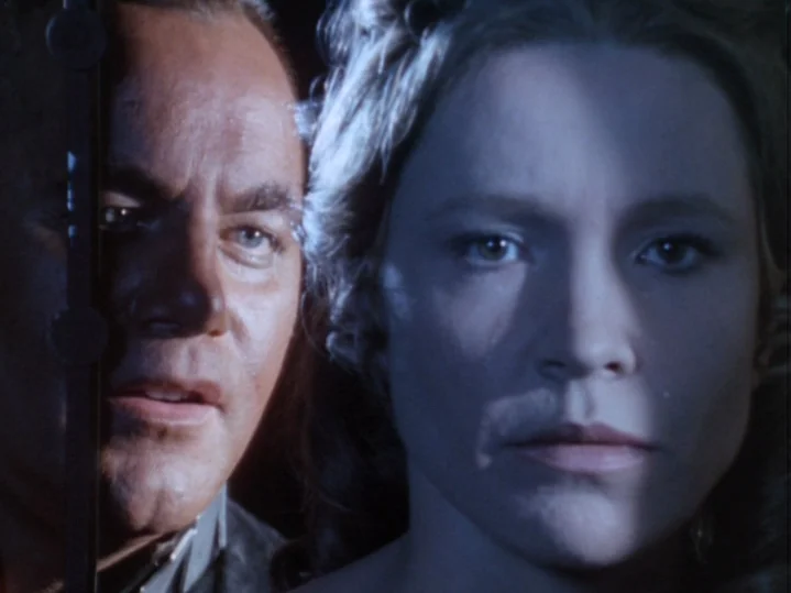 The Magic Flute (1975) movie still: closeup — A man and a woman are shown in close proximity in a dark space. They stare directly forward with…