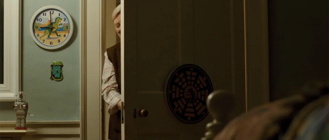 The New Daughter (2009) movie still: medium — A light blue-walled child's room features a dinosaur clock and a small toy robot. An older woman…