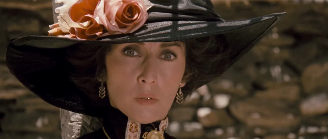 Duck, You Sucker (1971) movie still: closeup — A woman stands before a blurred dry-stone wall in natural outdoor light. She wears a wide-brimmed hat…