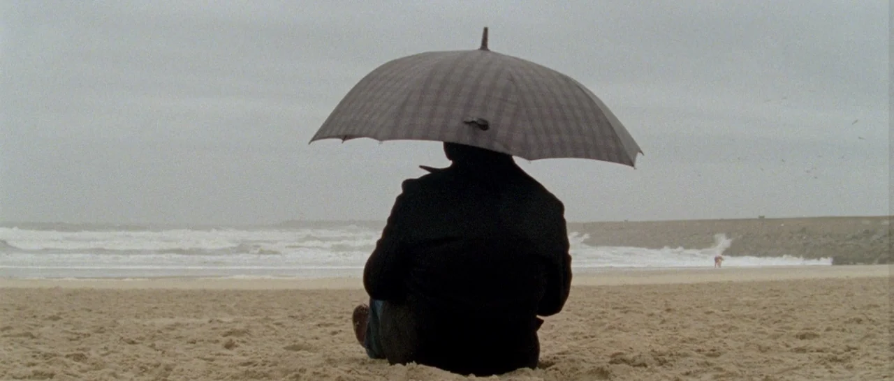 Arabian Nights: Volume 1 – The Restless One (2015) movie still: medium — A wide, flat beach on an overcast day with waves crashing against a jetty.…