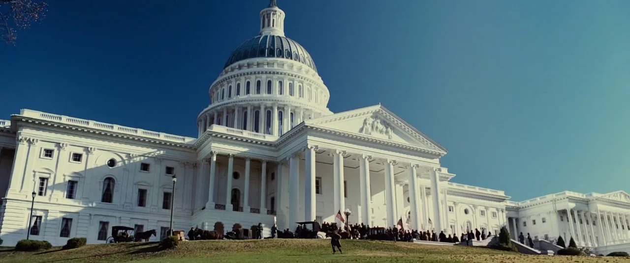 Lincoln (2012) movie still: establishing — The United States Capitol building stands with its white dome against a clear sky. A crowd of people…