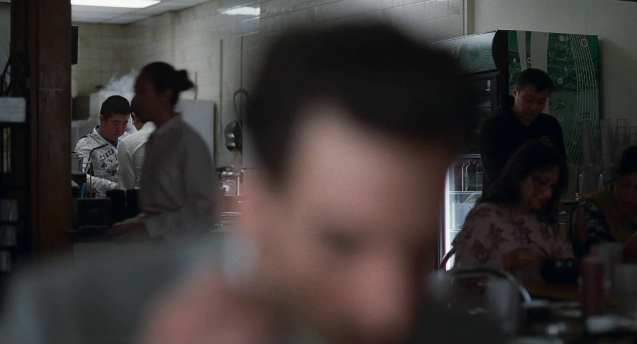 Matthias & Maxime (2019) movie still: medium — A utilitarian restaurant interior with tiled walls and a refrigerated drink display unit. Several…