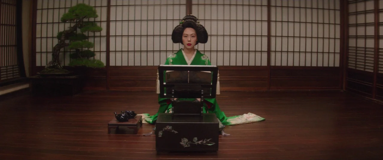 The Handmaiden (2016) movie still: medium — A traditional Japanese room features dark wooden flooring and shoji screen walls. A woman in a green…
