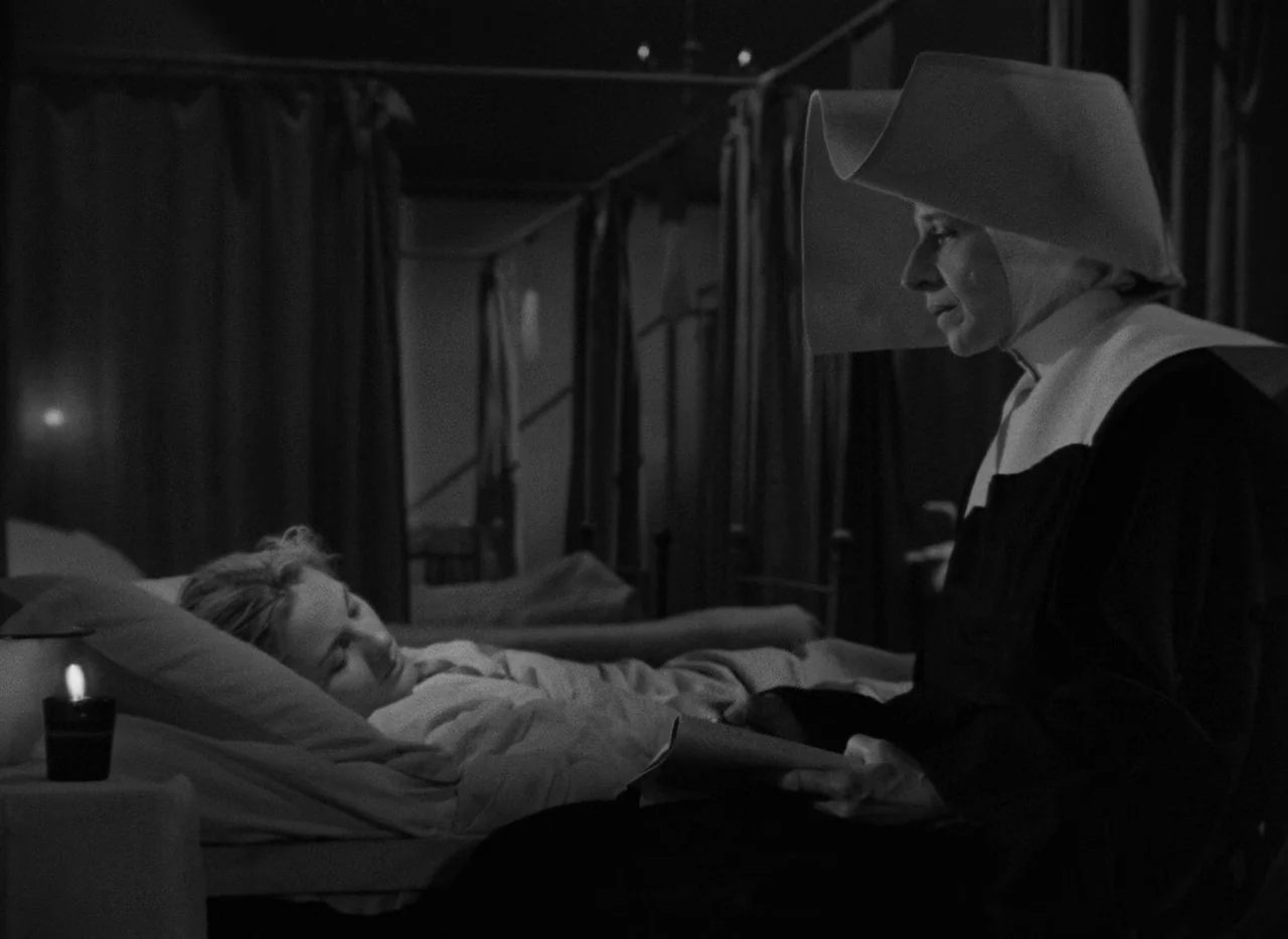 Letter From An Unknown Woman (1948) movie still: medium — A dimly lit room contains multiple iron-framed cots with fabric curtains. A nun in a…