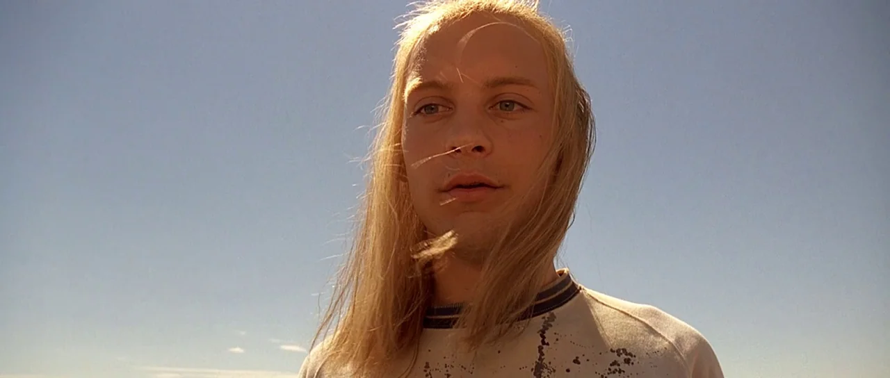Fear and Loathing In Las Vegas (1998) movie still: closeup — An open outdoor space under a bright, clear blue sky during the day. A young man with…