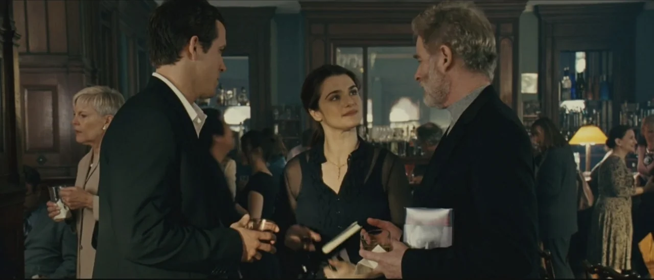 Definitely, Maybe (2008) movie still: medium — A crowded wood-paneled bar with patrons standing around while holding glasses of alcohol. A man, a…