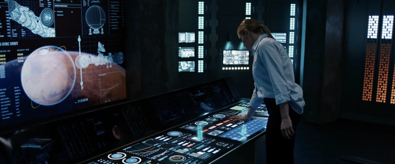 2036 Origin Unknown (2018) movie still: medium — A dark, modern mission control room features walls lined with glowing data monitors and consoles. A…
