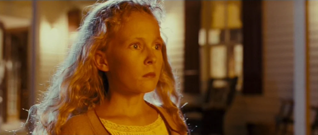 Paul (2011) movie still: closeup — A dark, out-of-focus house porch exterior is visible behind the girl. The young girl stares blankly ahead while…